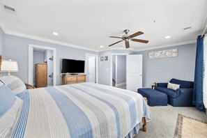 A bedroom with a bed, a television, a ceiling fan, and a blue sofa. - Sleeps 12, Private work Station, Elevator, Walk to Ocean, Garage Parking, PS4 (Myrtle Beach)