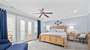 Une chambre à coucher avec un lit en bois, deux tables de chevet, une commode, une chaise et un ventilateur de plafond.