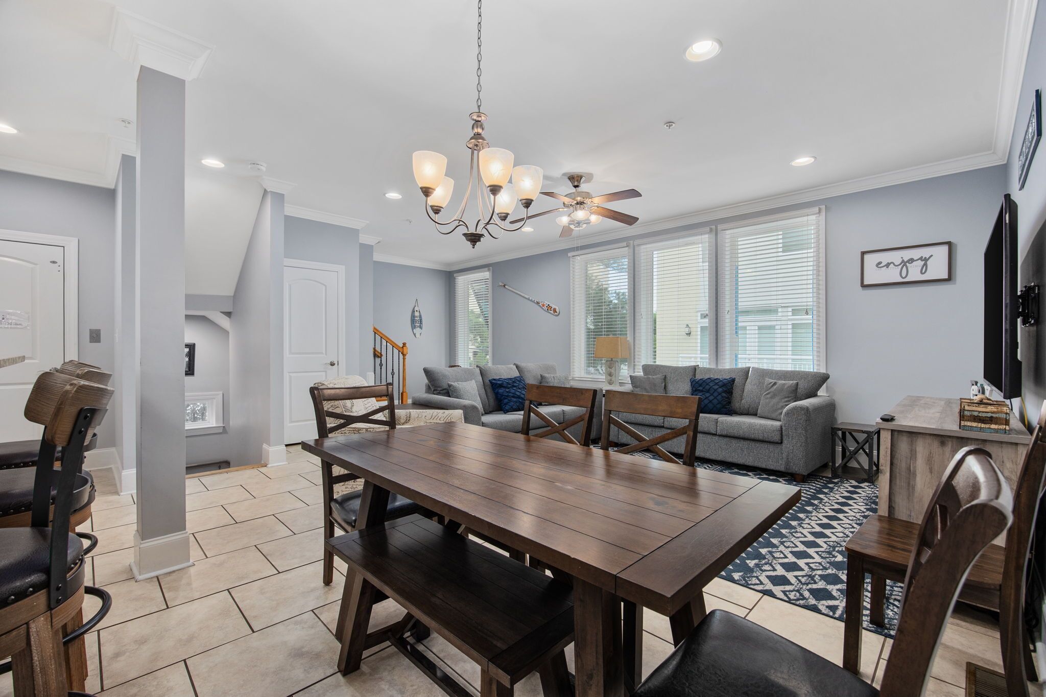 A dining area with a wooden table and chairs, a chandelier, and a ceiling fan.