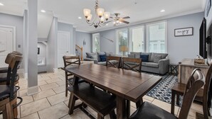 Un coin repas avec une table et des chaises en bois, un lustre et un ventilateur de plafond.
