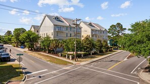 A multi-story residential building with a sloped roof, a driveway, and a street intersection. - Sleeps 12, Private work Station, Elevator, Walk to Ocean, Garage Parking, PS4 (Myrtle Beach)