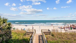 A beach with wooden walkways leading to the shore, a sandy beach, and the ocean. - Sleeps 12, Private work Station, Elevator, Walk to Ocean, Garage Parking, PS4 (Myrtle Beach)