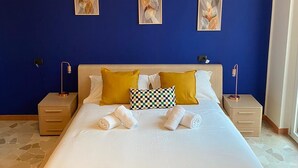 Una habitación de hotel con una cama grande, dos mesitas de noche y tres obras de arte colgadas en la pared.