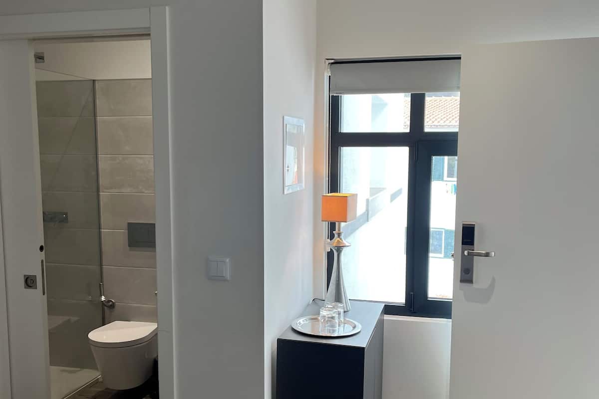 Un baño moderno con cabina de ducha de vidrio, inodoro y tocador con lámpara.