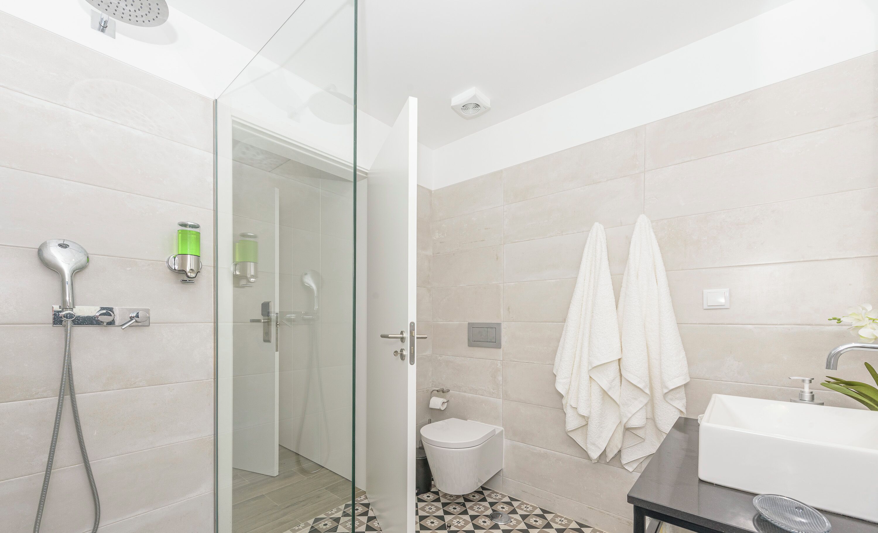 A modern bathroom with a glass shower enclosure, a toilet, and a sink with a mirror.
