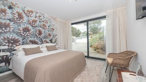 Un dormitorio con una cama grande, una silla, una mesita de noche y un mural de flores en la pared.
