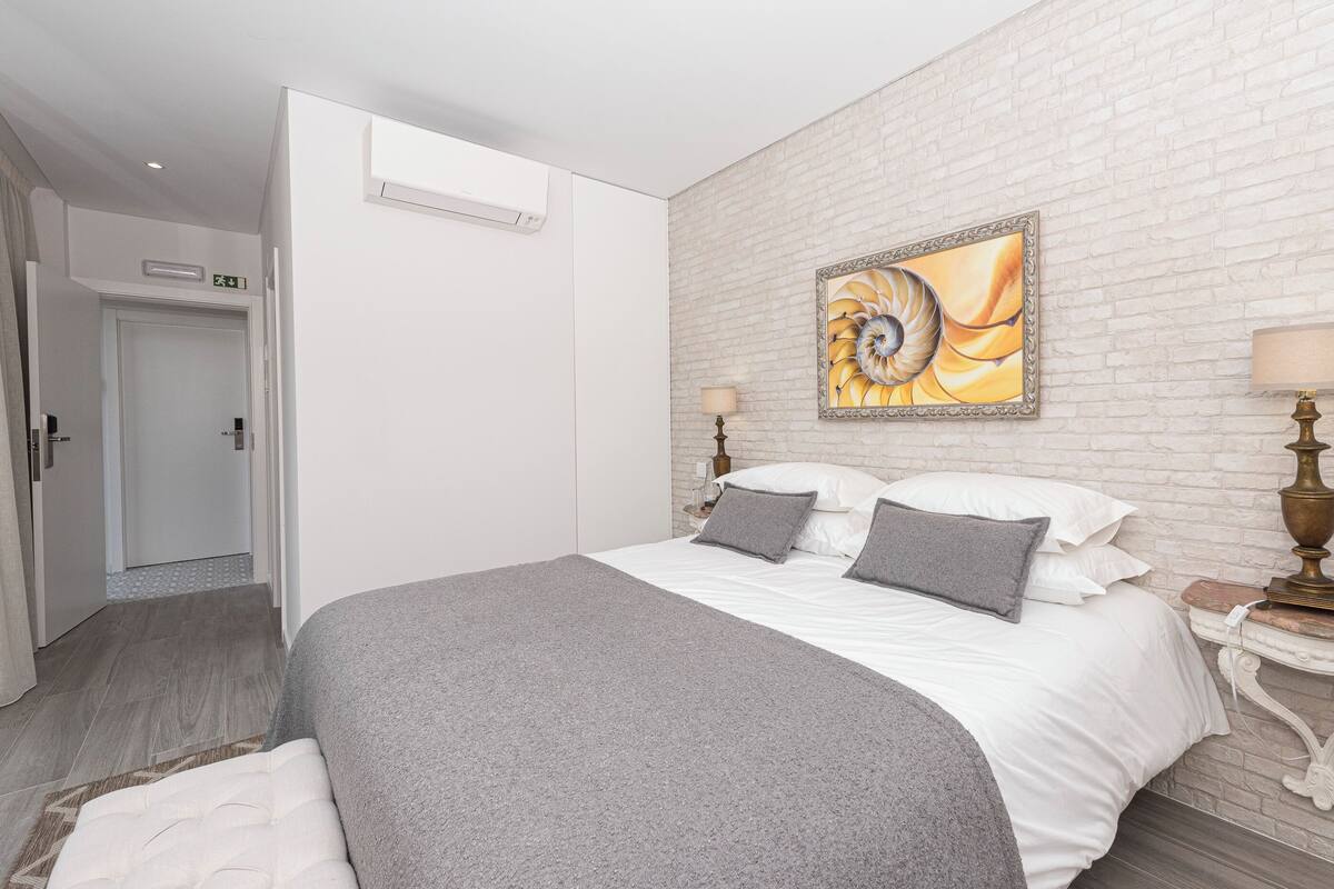 Una habitación de hotel con una cama, un muro de ladrillos blancos y un cuadro.