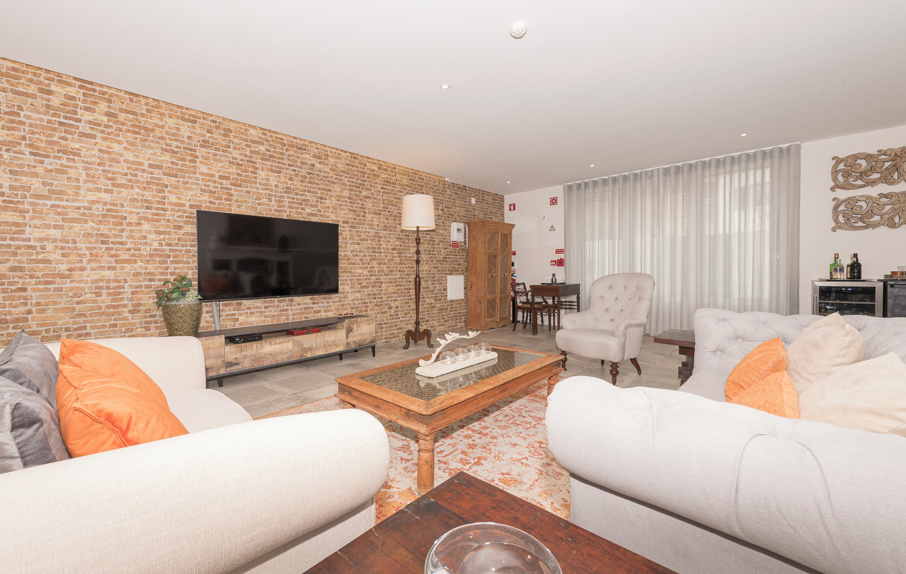 Ein Wohnzimmer mit Ziegelwand, Flachbildfernseher, Couchtisch und zwei Sofas.