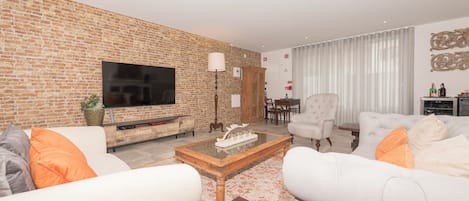 Ein Wohnzimmer mit Ziegelwand, Flachbildfernseher, Couchtisch und zwei Sofas.