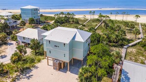 A beachfront property with multiple buildings, including a two-story house with a covered porch and a separate tower-like structure. - Beach House - Deepwater Dream by PHG (Port St. Joe)