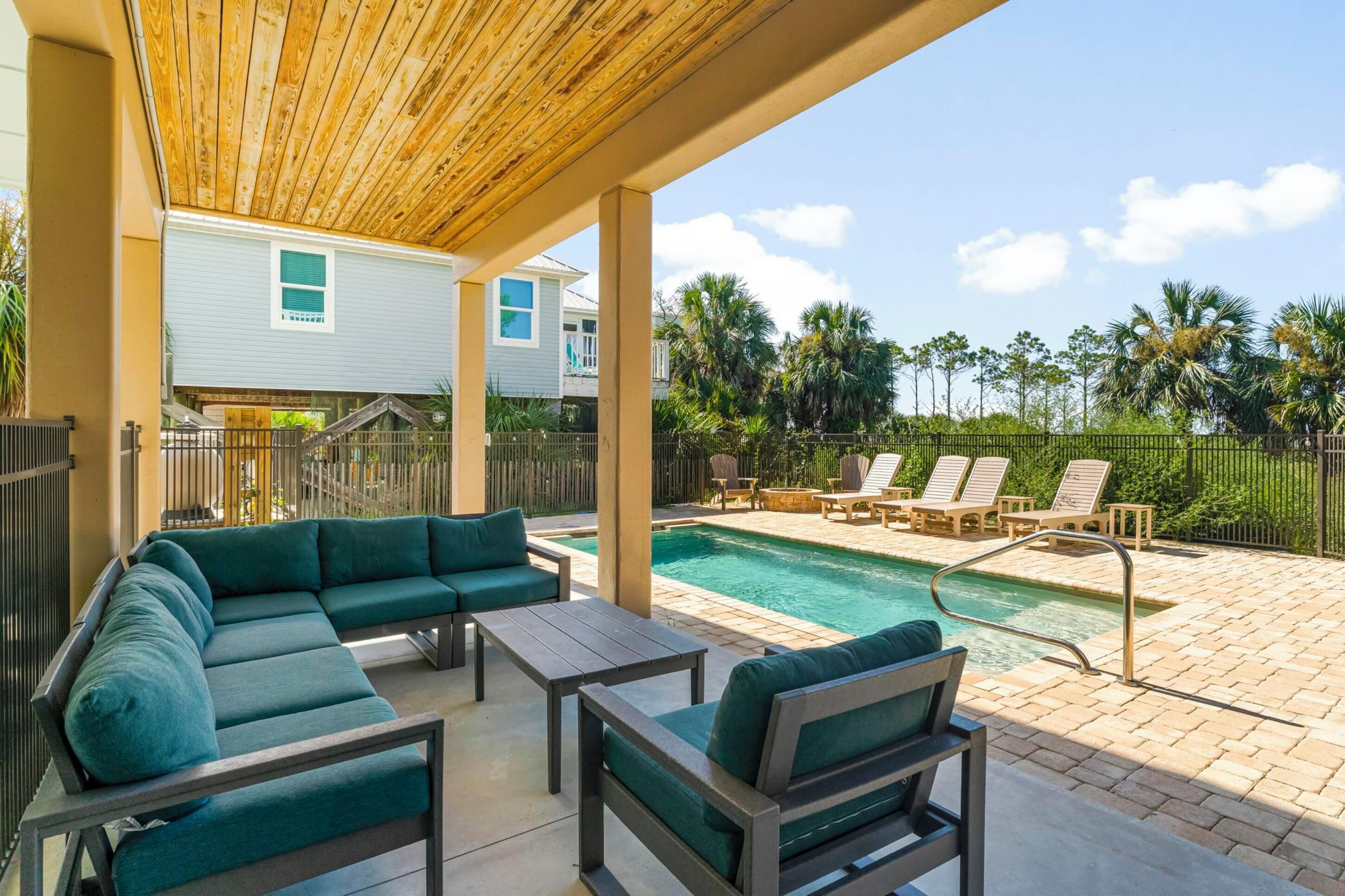 Un espace extérieur abrité comprenant une piscine, des chaises longues et une pergola en bois.