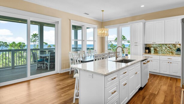 A spacious kitchen with a large island, white cabinetry, and a view of the outdoors. - Beach House - Deepwater Dream by PHG (Port St. Joe)