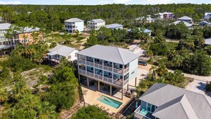 A multi-story residential building with a pool, surrounded by lush greenery and other houses. - Beach House - Deepwater Dream by PHG (Port St. Joe)