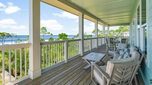 A covered porch with a view of the beach, wooden deck, and outdoor furniture. - Beach House - Deepwater Dream by PHG (Port St. Joe)