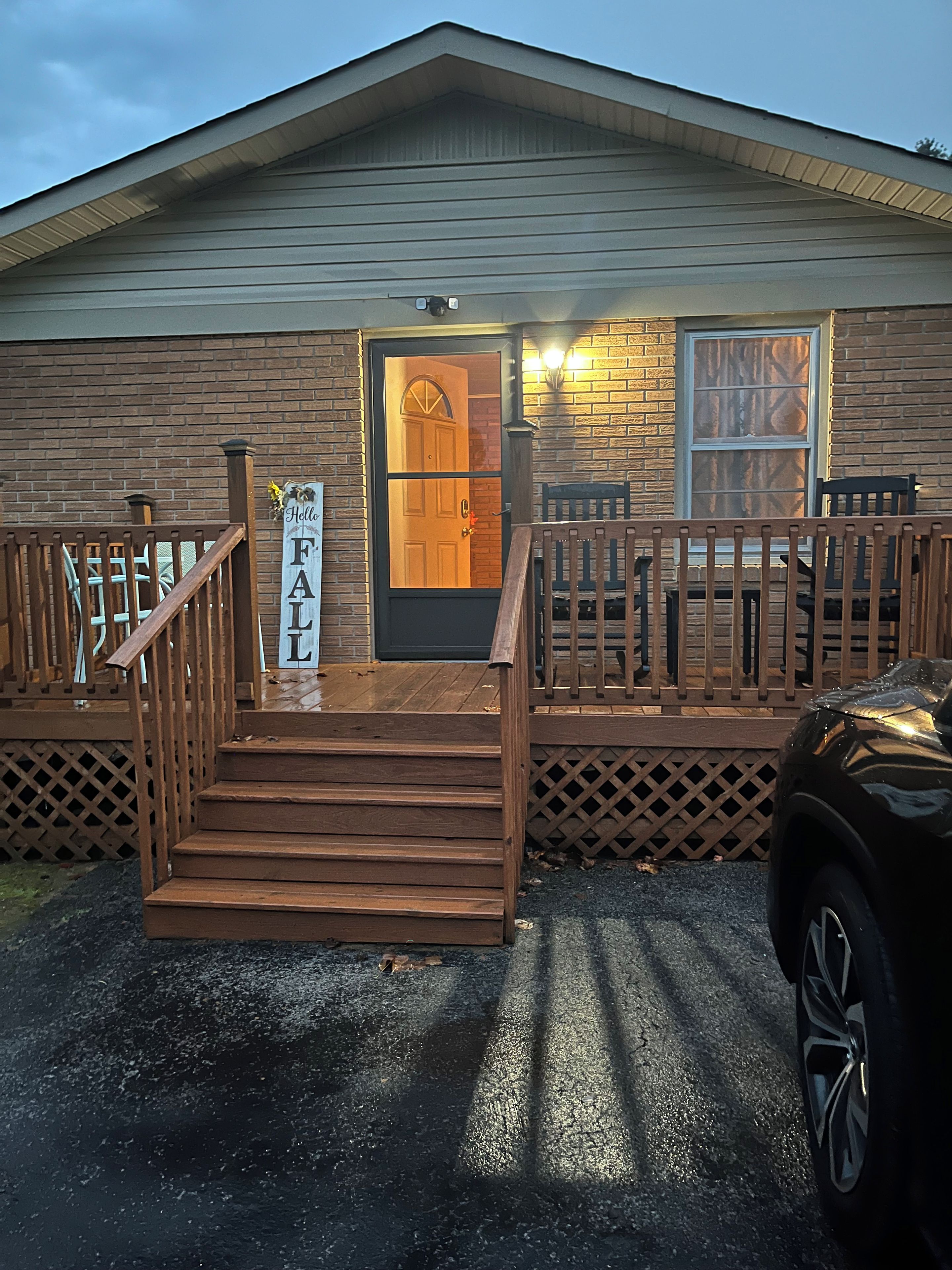 A wooden cabin with a front porch, a staircase, and a sign that reads 'Hello FALL'.