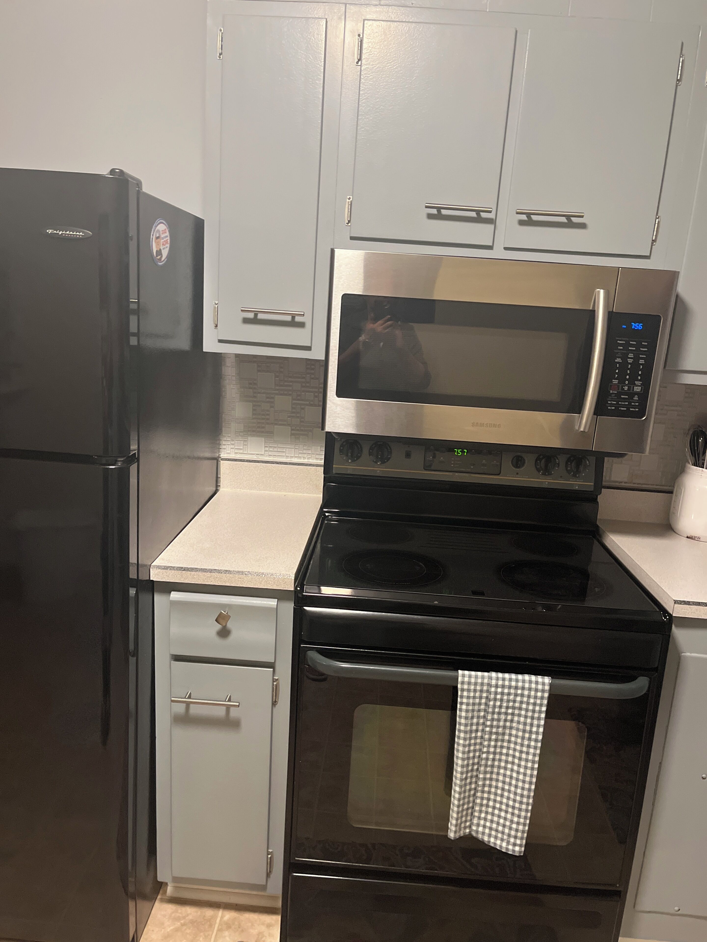A kitchen with a refrigerator, microwave, stove, oven, and a sink.