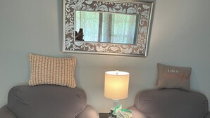 Una habitación con dos sillones grises, una mesita con una lámpara y un espejo en la pared.
