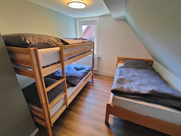 A dormitory room with bunk beds and a single bed.