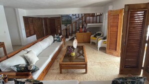 A spacious living room with a large sofa, a coffee table, and a staircase leading to another level. - RioMar Cumayasa. Nature, peace and quiet. Time out between river, sea and palm trees (La Romana)