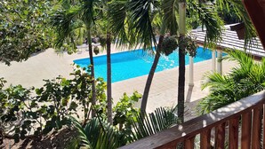 A wooden balcony overlooking a swimming pool surrounded by palm trees and tropical plants. - RioMar Cumayasa. Nature, peace and quiet. Time out between river, sea and palm trees (La Romana)