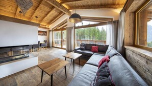 Un salon chaleureux avec un plafond en bois, un canapé, une table basse et un coin repas avec des chaises.