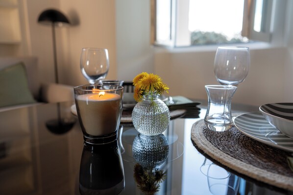 A dining table with a candle, a glass vase with yellow flowers, and a glass candle holder. - Villa Maderni Breathtaking (Como)