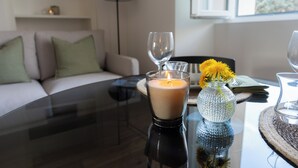 A modern living room with a glass table, a lit candle, a vase with yellow flowers, and a sofa with green cushions. - Villa Maderni Breathtaking (Como)