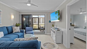 Ein modernes Wohnzimmer mit einem blauen Sofa, einem Couchtisch und einem an der Wand befestigten Fernseher.