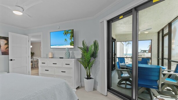 Ein Schlafzimmer mit Bett, Fernseher, Schreibtisch und Blick ins Freie.