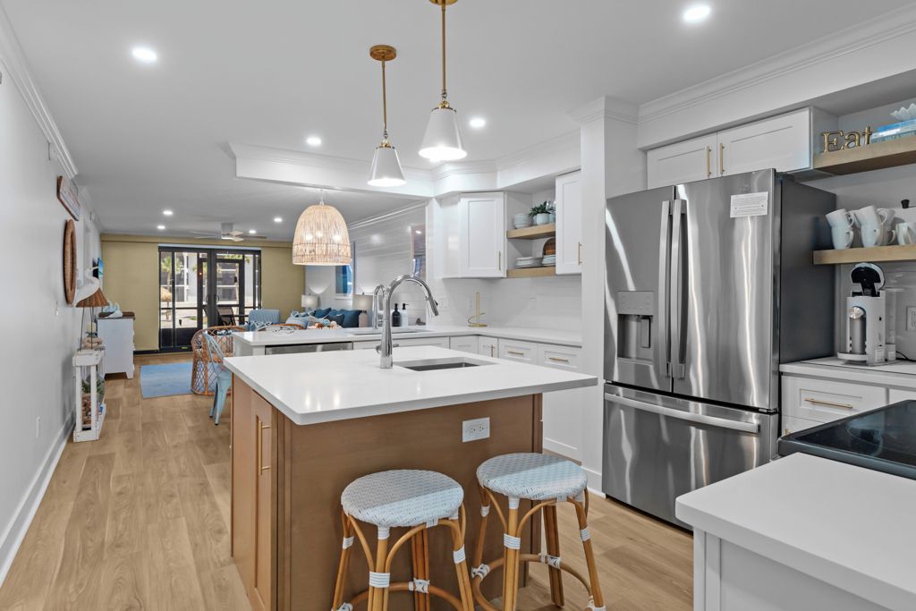 A modern kitchen with a central island, stainless steel appliances, and a hanging light fixture.