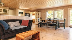 A cozy living room with a wooden ceiling, a dark brown sofa with cushions, a wooden coffee table, and a dining area with a wooden table and chairs. - 6 Person Holiday Home in Hals (Hals)