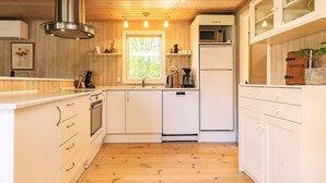 A modern kitchen with wooden flooring, white cabinetry, a stainless steel range hood, a microwave, and a refrigerator. - 6 Person Holiday Home in Hals (Hals)