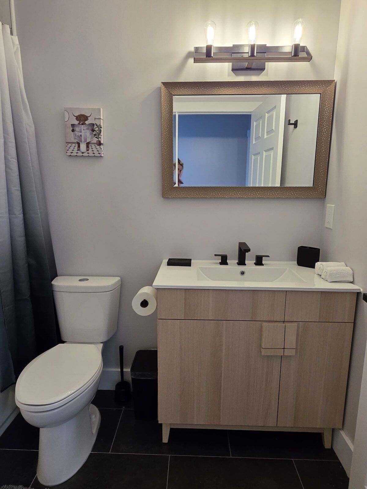 Een badkamer met toilet, wastafel en spiegel.
