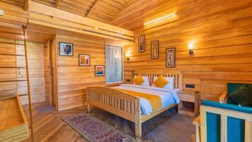 A wooden cabin bedroom with a bed, a nightstand, a dresser, a ladder, and a window.
