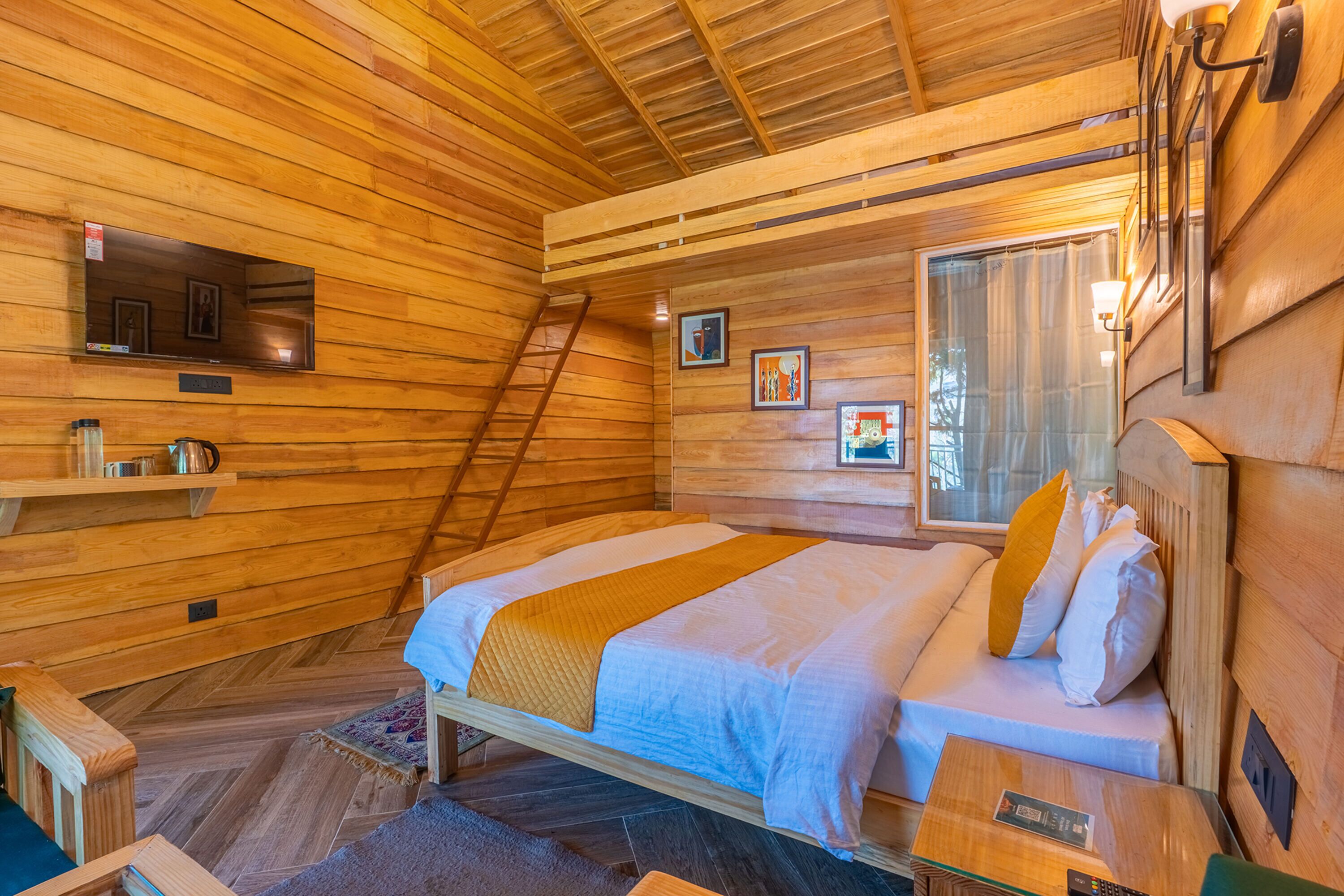 A wooden cabin room with a bed, a TV, a shelf with items, and a window.