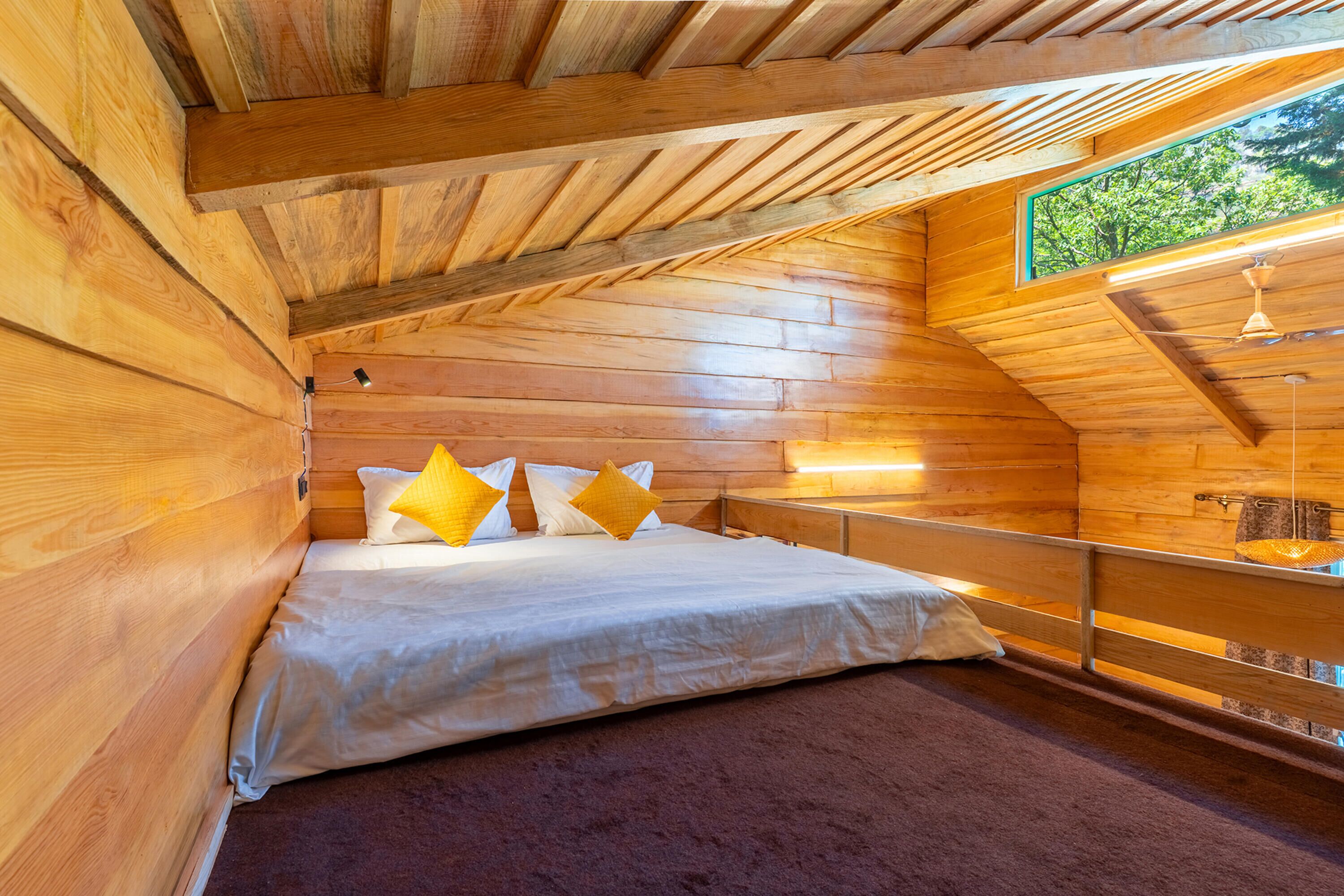 A wooden interior with a bed, a window, and a ceiling light.
