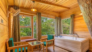 L'intérieur d'un chalet en bois, avec une baignoire, des meubles en bois et de grandes fenêtres.