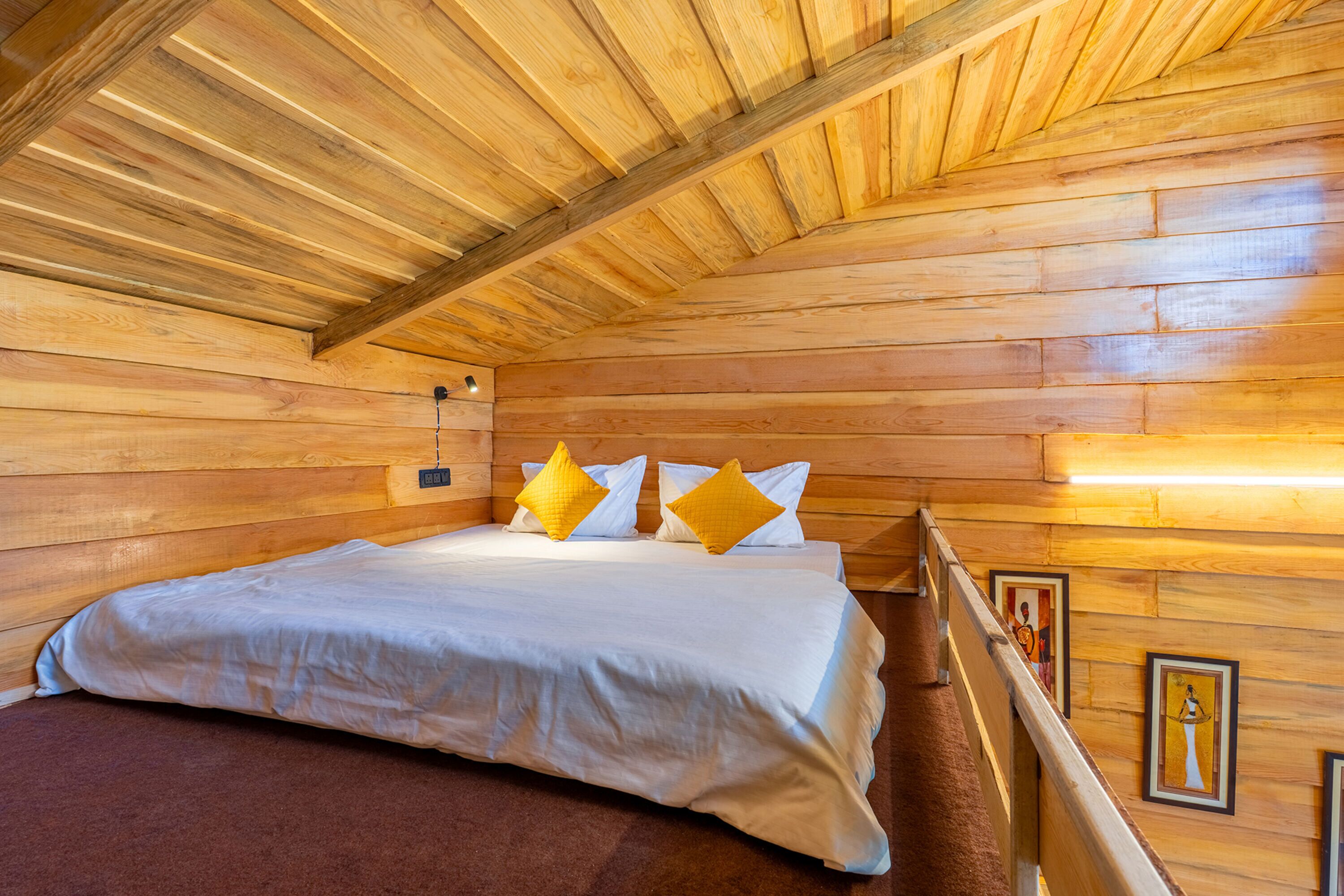 A wooden cabin bedroom with a bed, pillows, and a wooden ceiling.