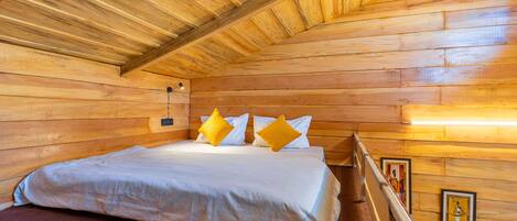 Un dormitorio de cabaña de madera con cama, almohadas y techo de madera.