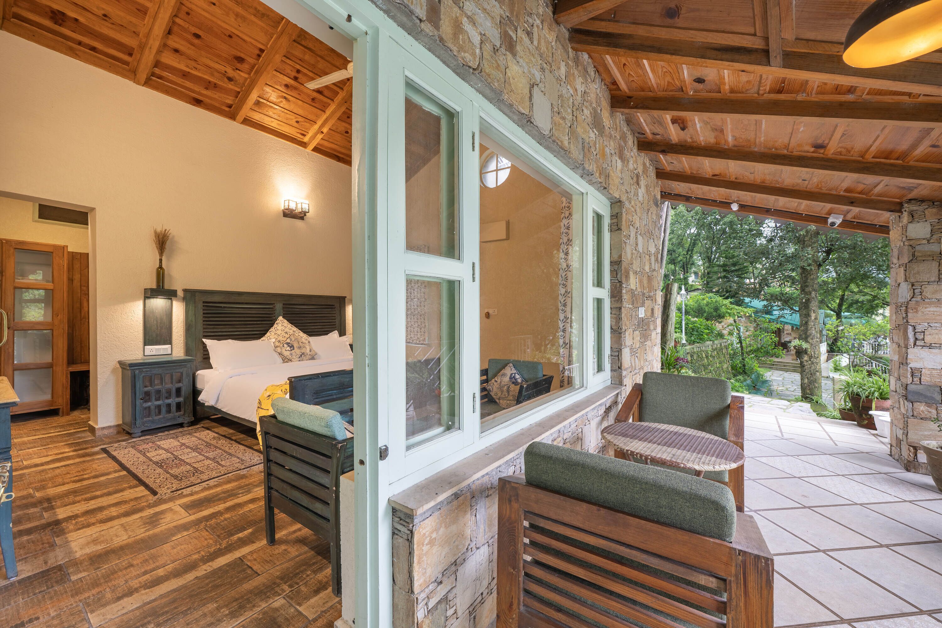 Un dormitorio con pared de piedra, techo de madera y vistas al jardín.
