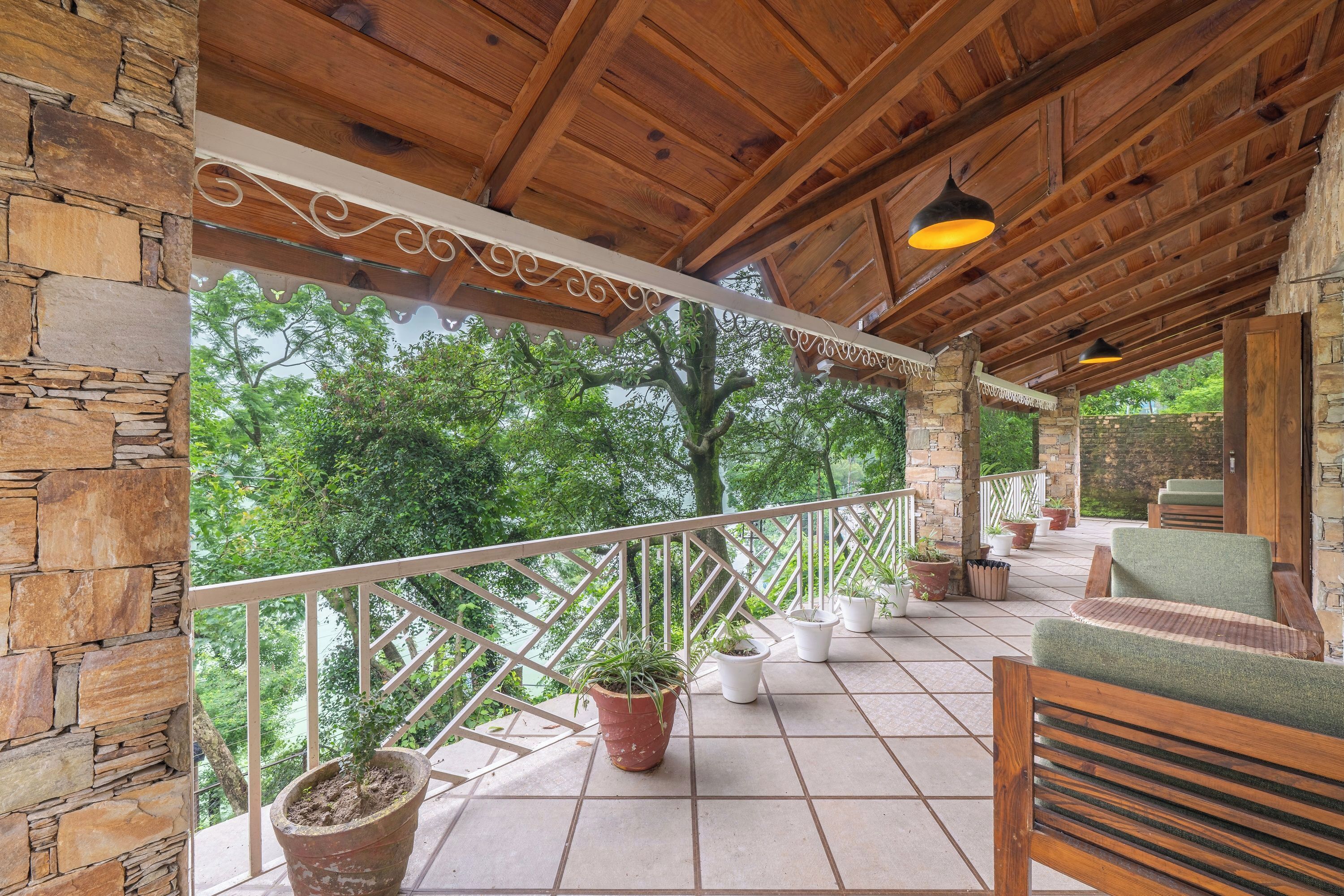A covered patio with wooden beams, potted plants, and outdoor furniture.