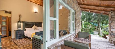 A bedroom with a large bed, a nightstand, and a window with a view of the outdoors.