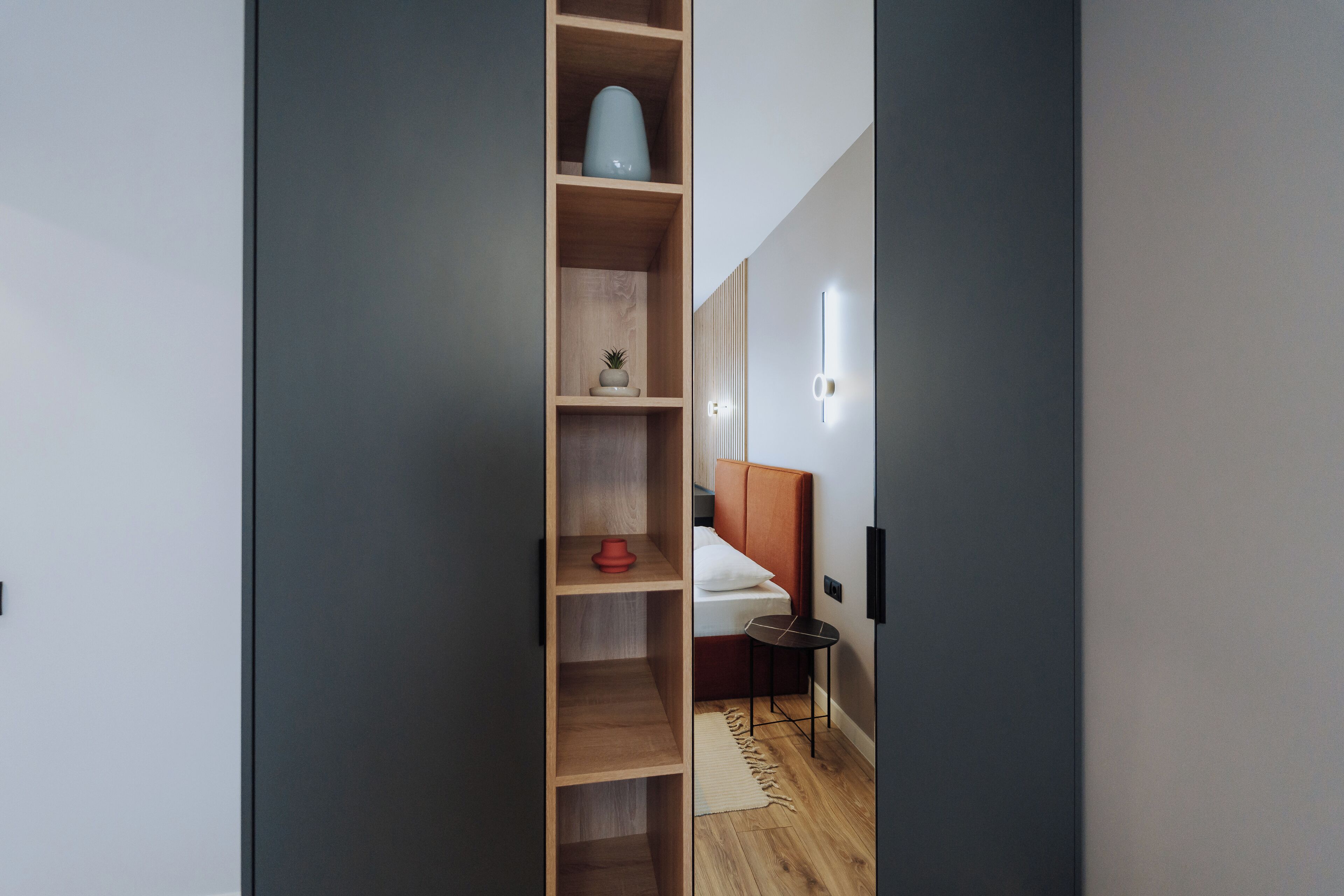 Ein modernes Schlafzimmer mit einem Holzschrank, einem Bett mit Kopfteil und einem Nachttisch.