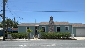 A two-story house with a stone chimney, a garage, and a white picket fence.