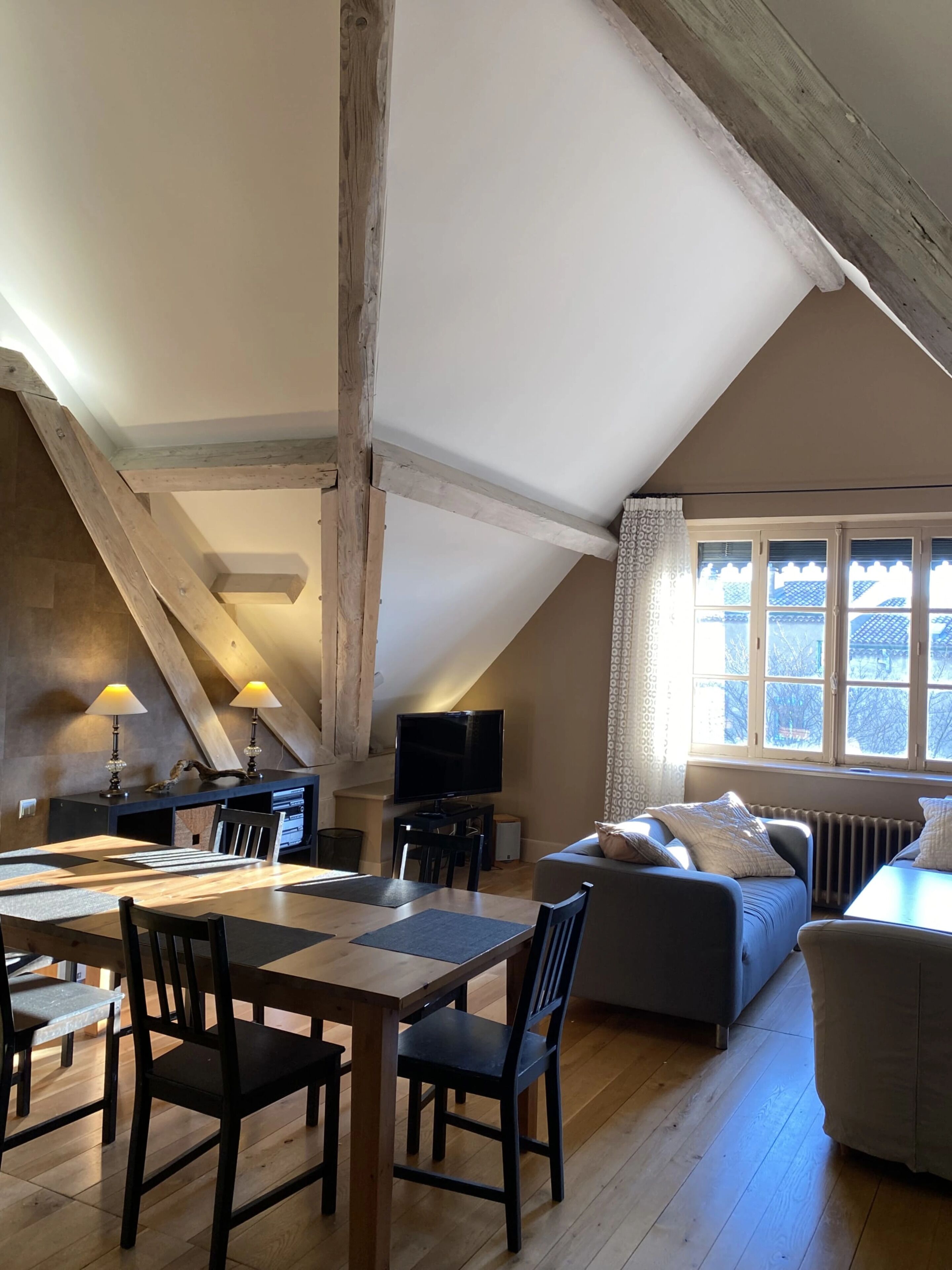 A cozy loft-style room with a dining area, a sofa, and a television.