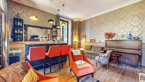 A bar area with a counter, bar stools, and a piano. There are two sofas and a patterned armchair. - Demeure Saint Louis (Carcassonne)