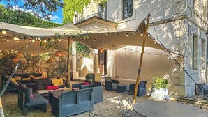 An outdoor patio with wicker furniture, string lights, and a covered area. - Demeure Saint Louis (Carcassonne)