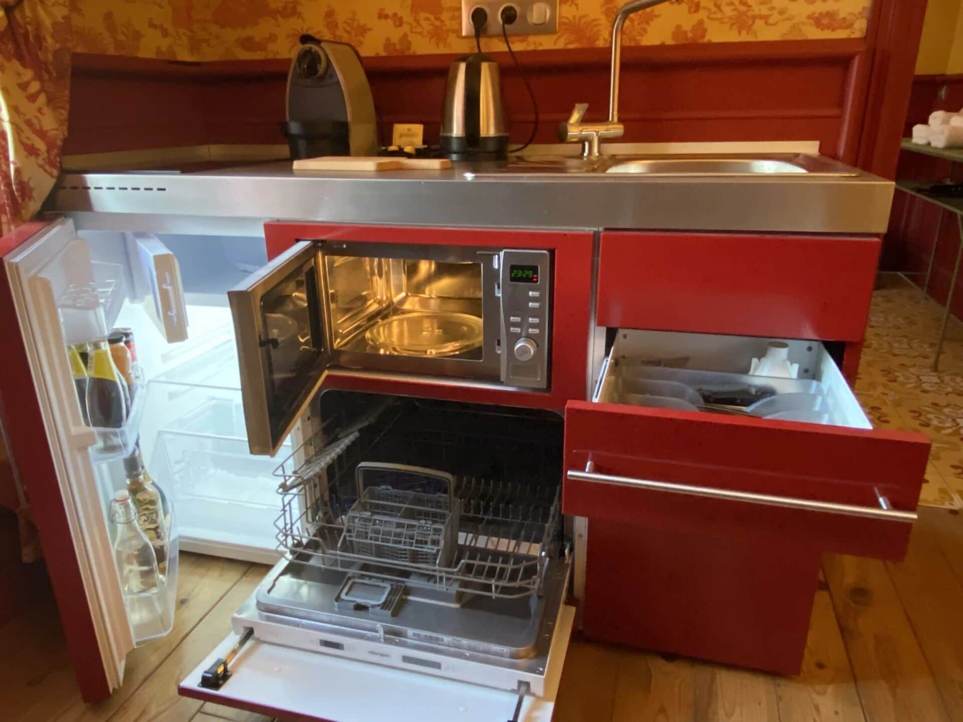 Une cuisine compacte équipée d’un four à micro-ondes encastré, d’une machine à café et d’un lave-vaisselle.