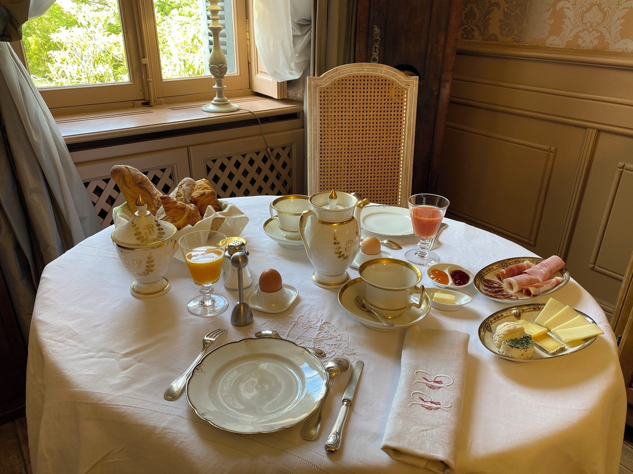 Una mesa de desayuno servida con diversos platos, incluyendo croissants, huevos y queso.