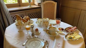 Una mesa de desayuno servida con diversos platos, incluyendo croissants, huevos y queso.